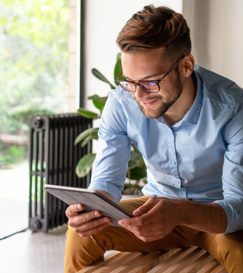 Mann mit Brille, der im sitzen auf sein Tablet schaut