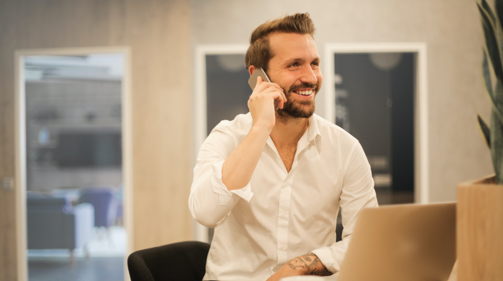 Glücklicher Berater mit Handy am Ohr im Büro