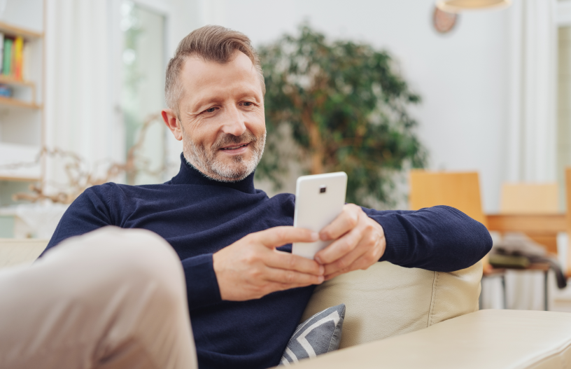 Mann auf Sofa mit Handy in der Hand