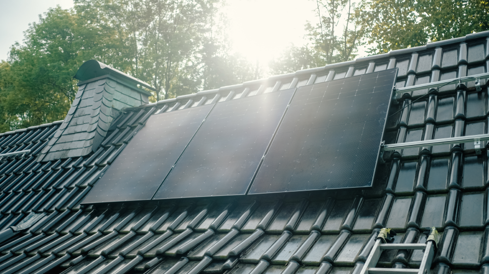 Solarmodule auf einem Dach mit Sonnenstrahlen im Hintergrund