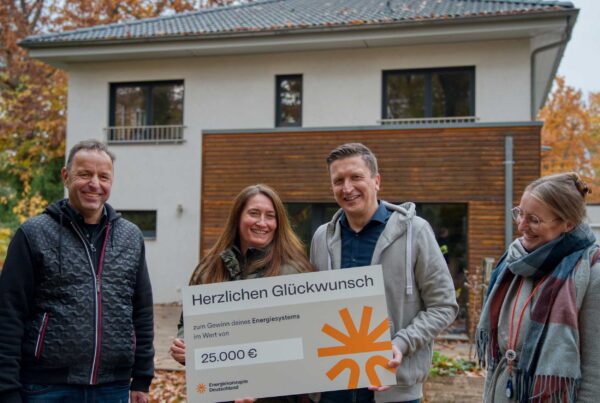 Die Gewinnerfamilie mit Gewinnspielcheck vor ihrem Haus