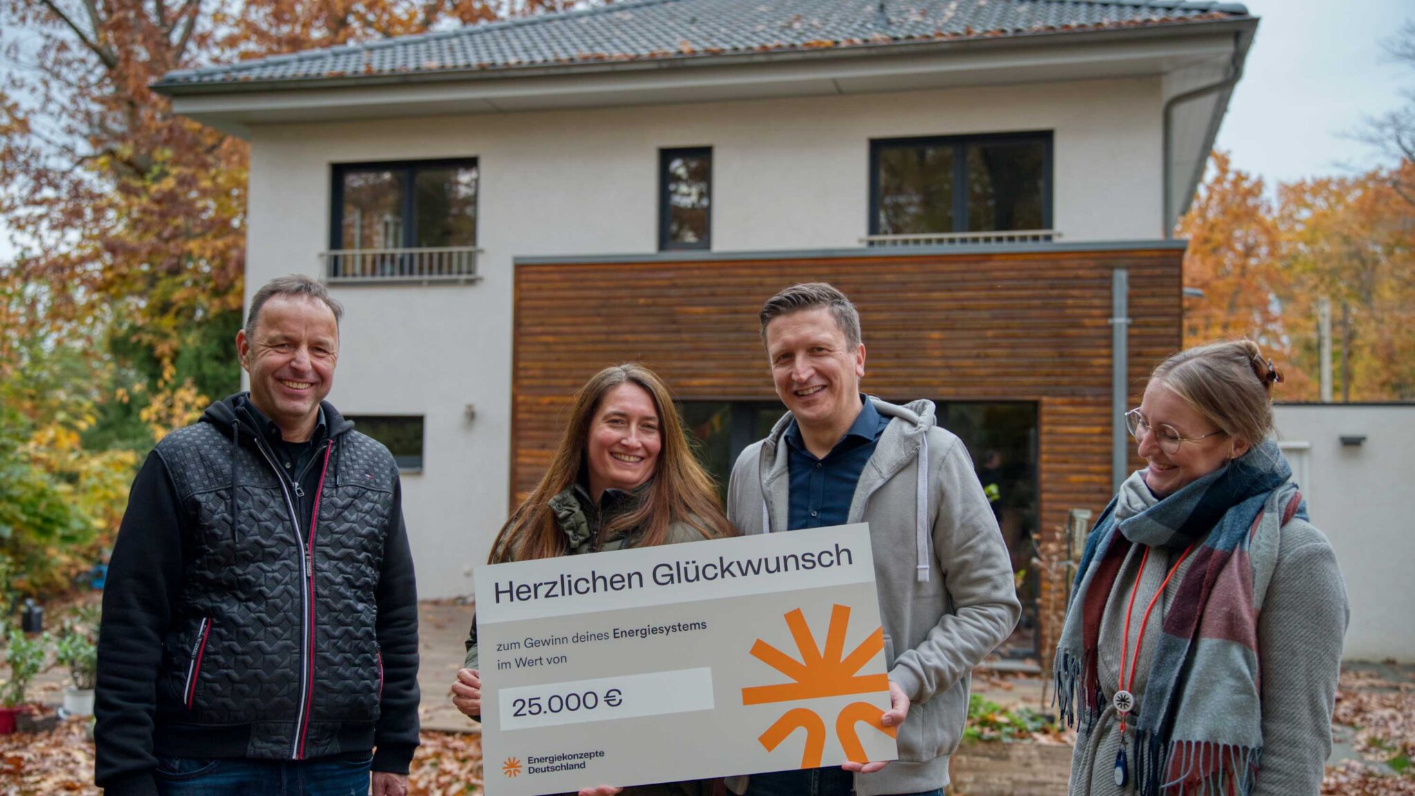 Die Gewinnerfamilie mit Gewinnspielcheck vor ihrem Haus