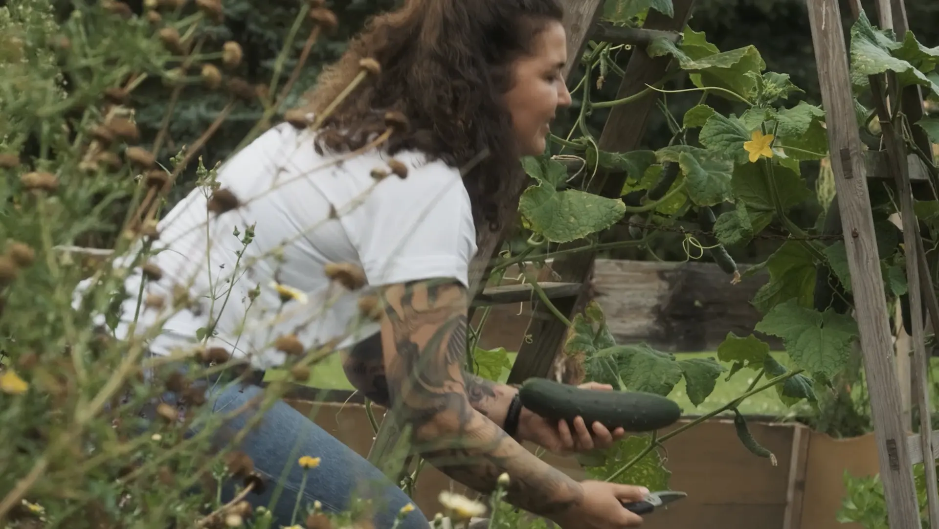 Bea im Garten mit einer Zucchini in der Hand