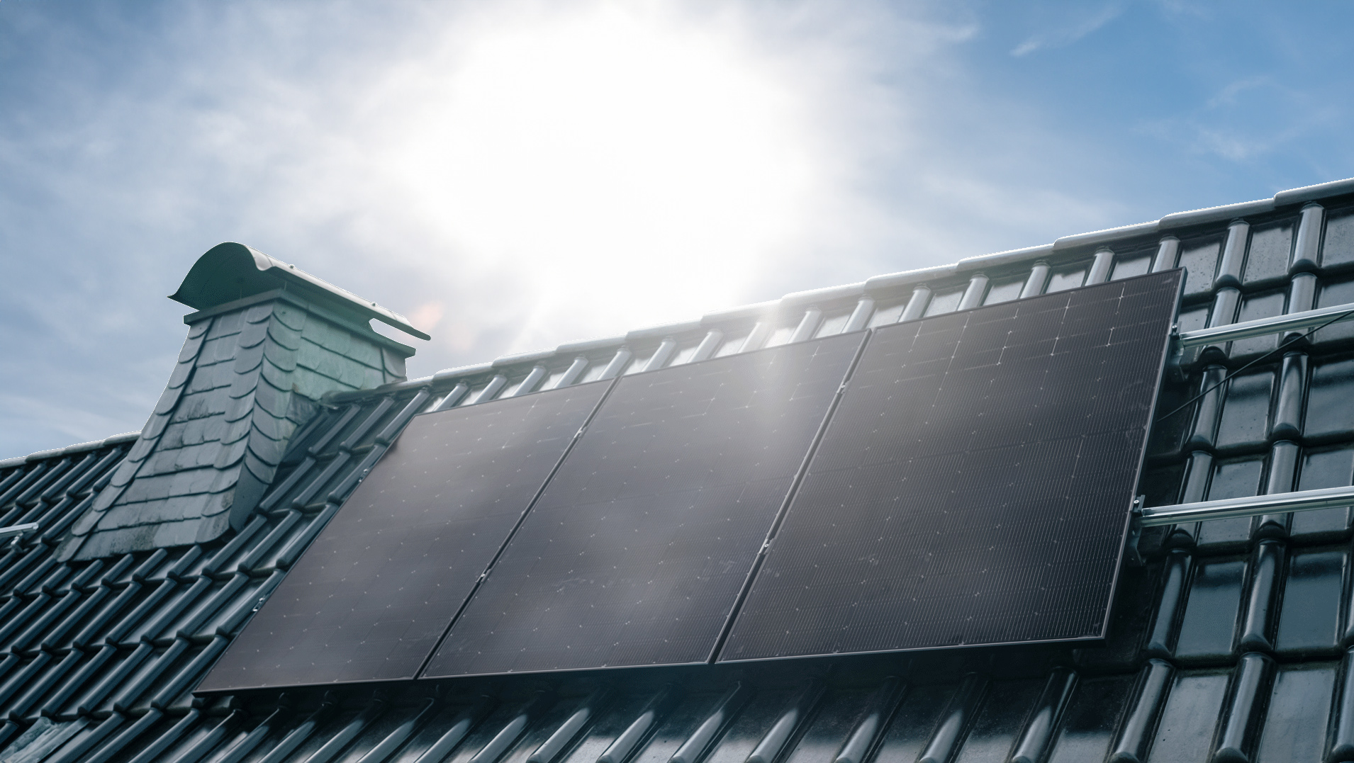 Ausschnitt eines Hausdachs mit drei Solarmodulen