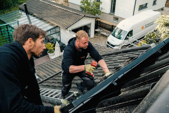 Zwei Handwerker von EKD, die eine Ampere.SolarPro Solaranlage auf einem Dach montieren